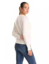 Buzo tejido en hilado fino, color blanco, con escote a la base y un collar decorativo de perlas y strass. Tiene mangas largas con un leve frunce en los hombros.