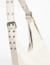 Cartera hobo color crudo de cuero sintético, con correa de hombro ajustable y múltiples cierres decorativos en el frente.