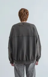 Buzo cuello redondo color gris oscuro con efecto desgastado, costuras expuestas y calce oversize crop.