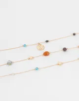 Set de tres collares cortos dorados con cuentas de colores y dijes metálicos.