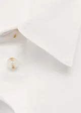 Camisa rosada de algodón con corte recto, cuello camisero, manga larga con puños abotonados, bolsillo de parche en el pecho y cierre frontal con botones.