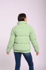Campera puffer acolchada color verde claro, con cuello alto, cierre con botones a presión y bolsillos laterales con cierre.