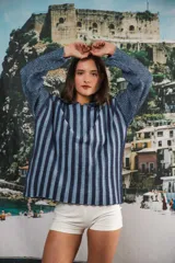 Buzo color beige con rayas horizontales en lurex dorado, cuello con medio cierre, corte oversized y logo tejido en el puño.