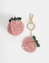 Set de accesorios para el pelo y llavero con espejo, ambos con forma de durazno rosado con hojas verdes.