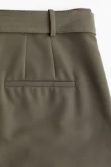 Pantalón de vestir color verde oliva, de tiro alto, corte amplio y largo hasta el tobillo. Incluye cinturón de tela con hebilla metálica.