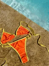 Conjunto de bikini naranja con ribete amarillo, compuesto por un corpiño triangular y una bombacha de corte clásico.