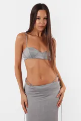 Conjunto de top y short color beige confeccionado en tela brillante. El top cuenta con arco metálico en el busto, tiras para atar en el hombro y ganchos lenceros en la espalda. El short es de tiro alto con cintura elastizada y bolsillos laterales.