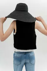 Chaleco negro de algodón con escote recto y corte recto. Presenta tres botones forrados al frente.