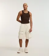 Bermuda baggy color crema, confeccionada en algodón y poliéster. Cuenta con cintura elástica ajustable con cordón y bolsillos cargo laterales.