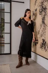 Vestido negro de noche con mangas 3/4, cuello en V con detalles de cuero entrelazado, terminación en flecos y tajos laterales.