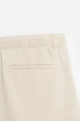 Bermuda negra regular fit confeccionada en tejido con mezcla de algodón y lino. Cintura elástica ajustable con cordón. Pliegues frontales. Bolsillos laterales y traseros de vivo. Cierre frontal con cremallera y botón.