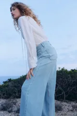 Pantalón de jean celeste de pierna ancha, tiro alto, con bolsillos de parche delanteros y traseros.