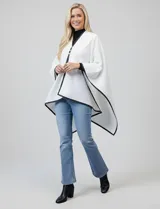 Ruana blanca de tejido soft, con ribetes en eco cuero negro. Presenta un cierre frontal con botones metálicos dorados.