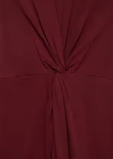 Vestido midi color borgoña, sin mangas y cuello redondo, con detalle de nudo drapeado en la cintura.