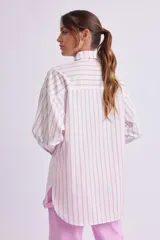 Camisa oversize blanca con rayas verticales rosas, de manga larga con puños abotonados, cuello clásico y bolsillo de parche en el pecho.