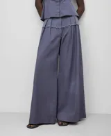 Pantalón ancho color gris azulado, de lino y algodón, con pinzas delanteras, canesú en delantero y espalda en tejido a contraste, cinturilla elástica en espalda y bolsillos laterales.