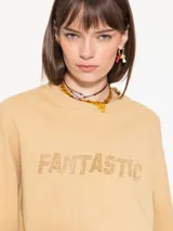 Buzo color beige de punto, con calce amplio y mangas largas. Estampa frontal con la palabra "Fantastic" con strass y logo bordado en la espalda.