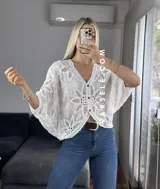 Blusa blanca de encaje con mangas amplias, escote en V y cierre frontal con botones.