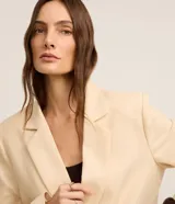 Blazer oversized color beige confeccionado en viscolino, con solapas en el cuello, botones delanteros y solapas delanteras que simulan bolsillos.
