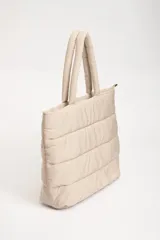 Bolso tipo tote bag color beige, con diseño acolchado horizontal y doble asa de hombro.