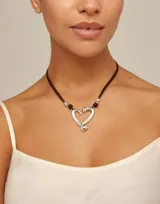 Collar Uno de 50 con doble cordón de cuero marrón y dije central de corazón plateado con forma de clavo.