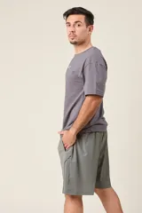 Bermuda deportiva de nylon color gris, de corte suelto, con cintura elástica y cordón de ajuste. Cuenta con detalles de líneas en los costados y bolsillos con cierre.