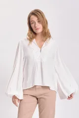 Blusa blanca de mangas largas abullonadas con cuello en V y detalle de botón en el frente.