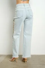 Pantalón de jean celeste con lavado claro, tiro alto, corte recto y apliques de gemas en aberturas laterales.