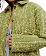 Chaqueta acolchada con estampado floral en tonos azul y beige, cuello camisero y cierre frontal con botones.