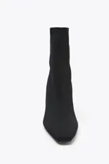 Botín negro de tejido elástico con puntera fina y tacón cuadrado.
