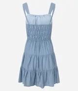 Vestido corto color beige, con escote recto, breteles medianos y lazo decorativo en el centro del busto. Presenta costura fruncida en la cintura y falda con babados en capas.