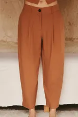Pantalón color crema de tiro alto con pinzas delanteras y cintura elástica en la espalda. Tiene bolsillos delanteros y traseros.
