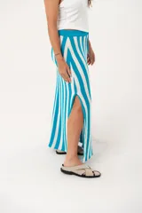 Falda larga tejida a rayas verticales turquesas y blancas, con pretina elástica y tajos laterales.