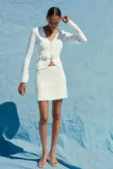Minifalda blanca de punto liso, tiro alto, cintura elástica y corte evasé.