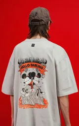 Remera color gris claro de corte oversize, con cuello redondo y mangas cortas. Estampado en la espalda con Mickey y Minnie Mouse sentados sobre una roca, con llamas y el texto 'Hello Darling'.