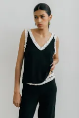Musculosa negra con escote en V y volados blancos en el escote y las sisas.