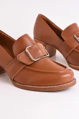 Mocasín de cuero color marrón con hebilla metálica plateada y taco de madera.