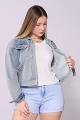 Campera de jean de lavado celeste claro, con diseño clásico de cuello y botones metálicos. Presenta detalles de pequeños brillos o tachas plateadas sobre la tela, especialmente visibles en los bordes de los bolsillos y costuras.