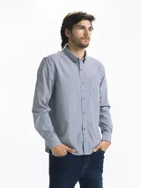 Camisa celeste y blanca a rayas verticales, de manga larga y corte clásico. Tiene cuello abotonado y bolsillo en el pecho.