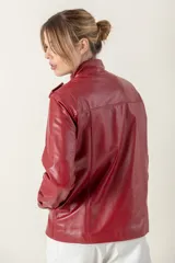 Campera roja de cuero ovino italiano, con charreteras en los hombros, bolsillos laterales, broches ocultos en el frente y broches a la vista en cuello y puños.