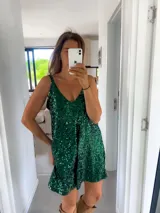 Vestido corto verde esmeralda cubierto de lentejuelas, con escote en V y tirantes finos.