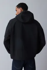 Campera rompevientos negra de nylon repelente al agua con protección UV, corte regular, cierre frontal, capucha con cordón de ajuste elástico, puños elásticos, bolsillos laterales y bolsillo interior con cierre, forro de malla y cordón de ajuste elástico oculto en el bajo.