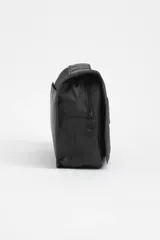 Necesser de viaje negro con cierre de cremallera y asa de transporte. Tiene un parche rectangular con el logo de un avión y la palabra "TRAVEL".