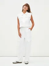 Chaleco corto color blanco, con cuello camisero, sin mangas y con bolsillos frontales.