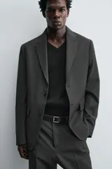 Blazer regular fit color gris oscuro con diseño de cuadros, confeccionada en tejido con lana. Tiene cuello con solapas de muesca, manga larga con puños abotonados, bolsillo de vivo en el pecho, bolsillos de solapa en la cadera, bolsillo interior, aberturas en la espalda y cierre frontal con botones.