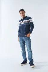 Remera tipo polo de manga larga azul marino con rayas horizontales blancas, grises y rosadas en el pecho. Tiene cuello clásico con botones y logo estampado en el pecho. Corte regular.