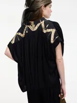 Blusa negra de manga corta con escote en V y bordados en la espalda.