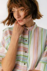 Camisa oversize con cuello mao, manga corta con terminación en puño, botones de metal a la vista y tajos laterales.