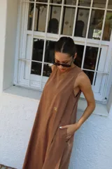 Vestido largo gris sin mangas, con escote redondo, bolsillos laterales y logo bordado en el frente.