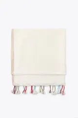 Pañuelo rectangular color crudo, confeccionado en lino, con borde color beige y flecos de hilo blanco con detalles de colores.